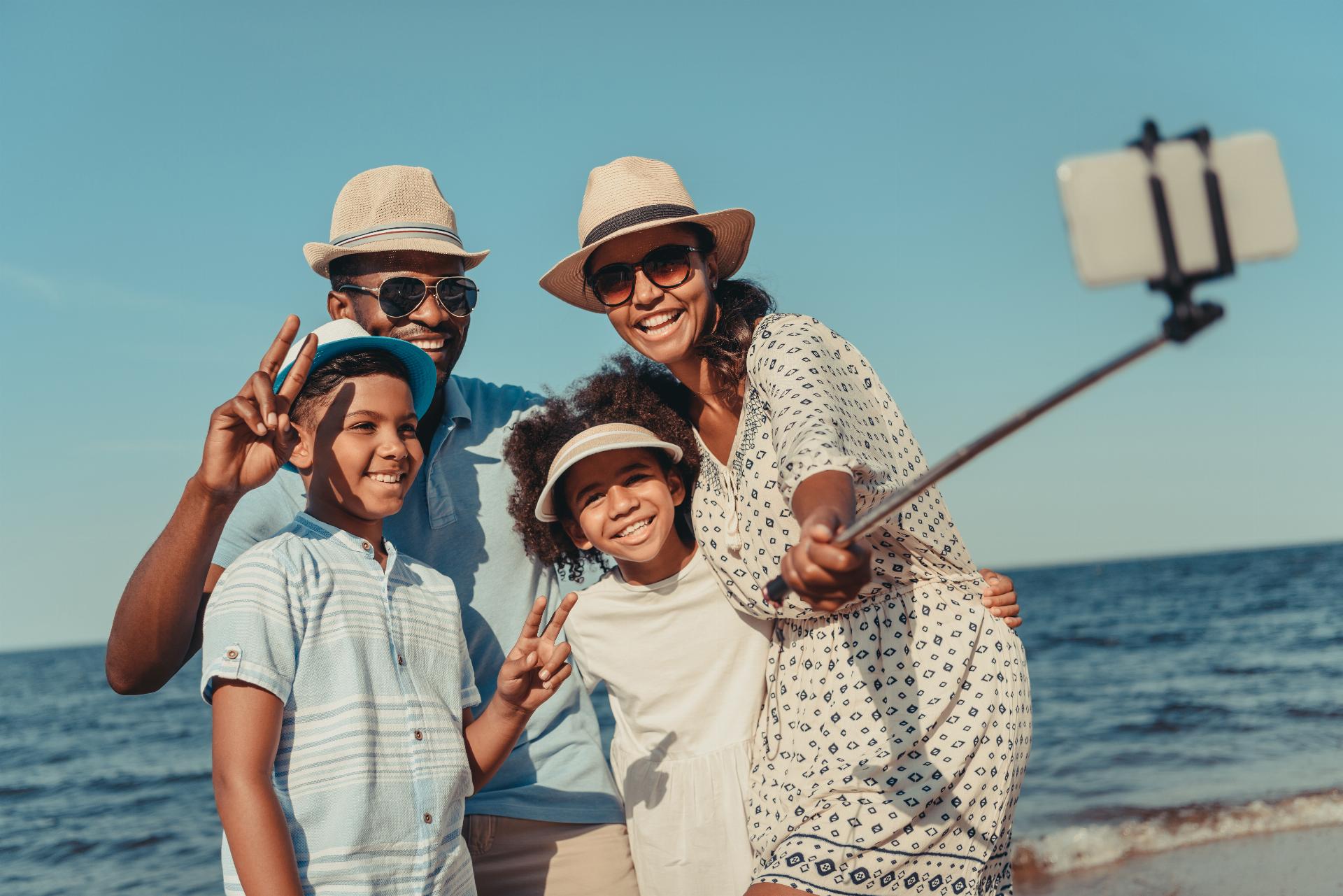 happy african american family taking selfie with smartphone on beach