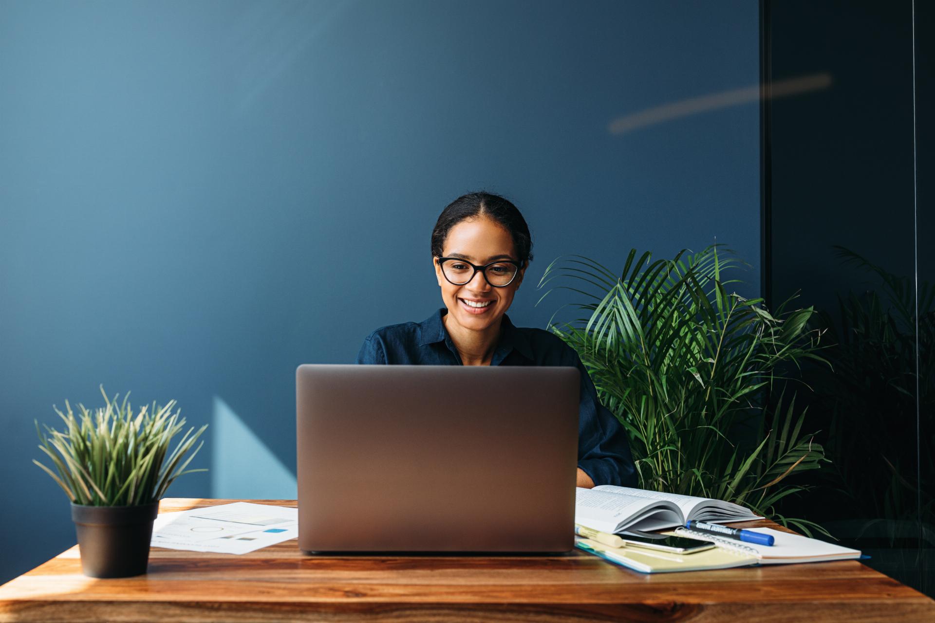 Smiling entrepreneur sitting at home working on laptop computer